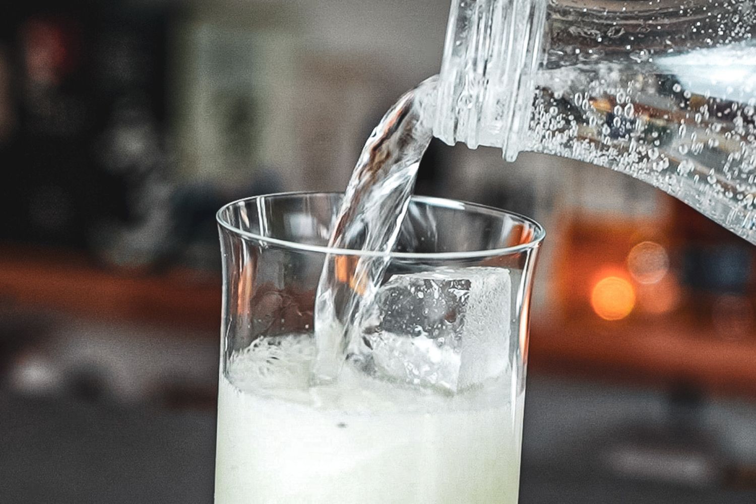 Wasser wird in ein Glas mit Eiswürfeln gegossen.