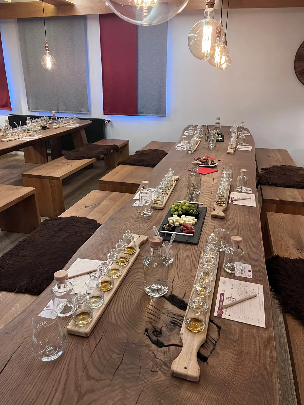 Gedeckte Tafel mit Whisky-Tasting-Brettern und Snack-Platte im Verkostungssaal der Schlitzer Destillerie
