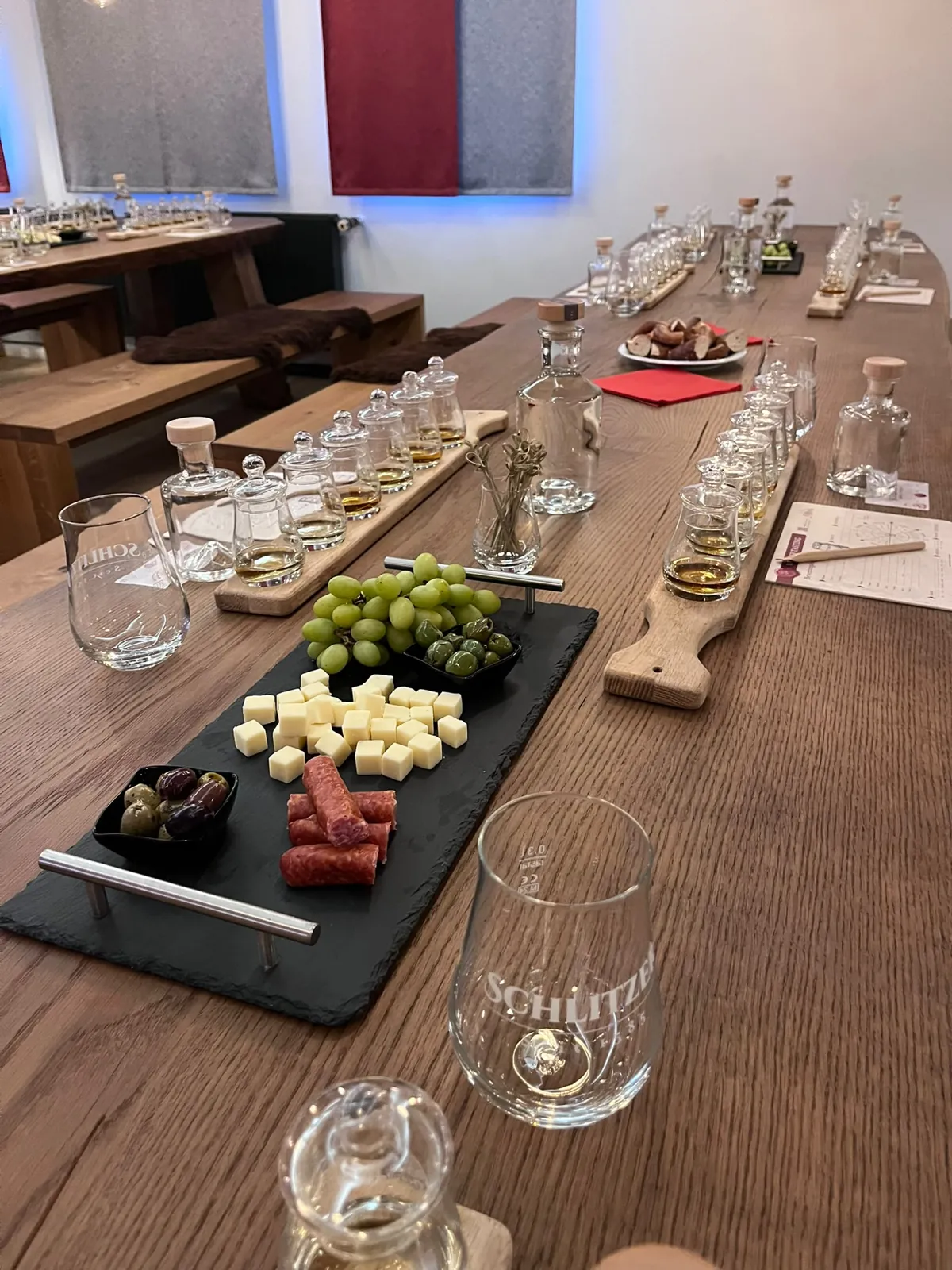 Schieferplatte mit Käsewürfeln, Salami, Oliven und Trauben neben Whisky-Gläsern beim Tasting in Schlitz