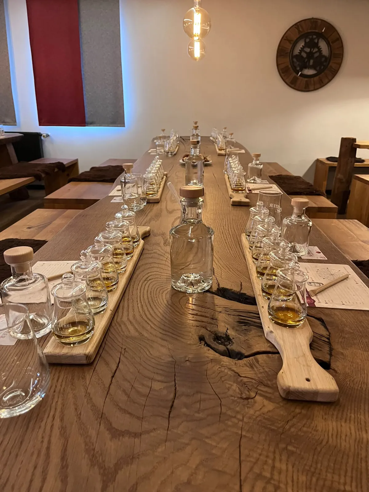 Lange Eichentafel mit Baumkante, eingedeckt mit Tasting-Brettern, Wasserkaraffen und Bewertungsbögen für ein Whisky-Tasting