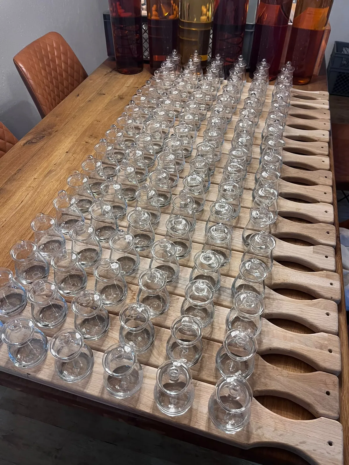 Dutzende leere Nosing-Gläser mit Glasdeckeln auf Eichenbrettern bei der Vorbereitung eines Whisky-Tastings in der Schlitzer Destillerie