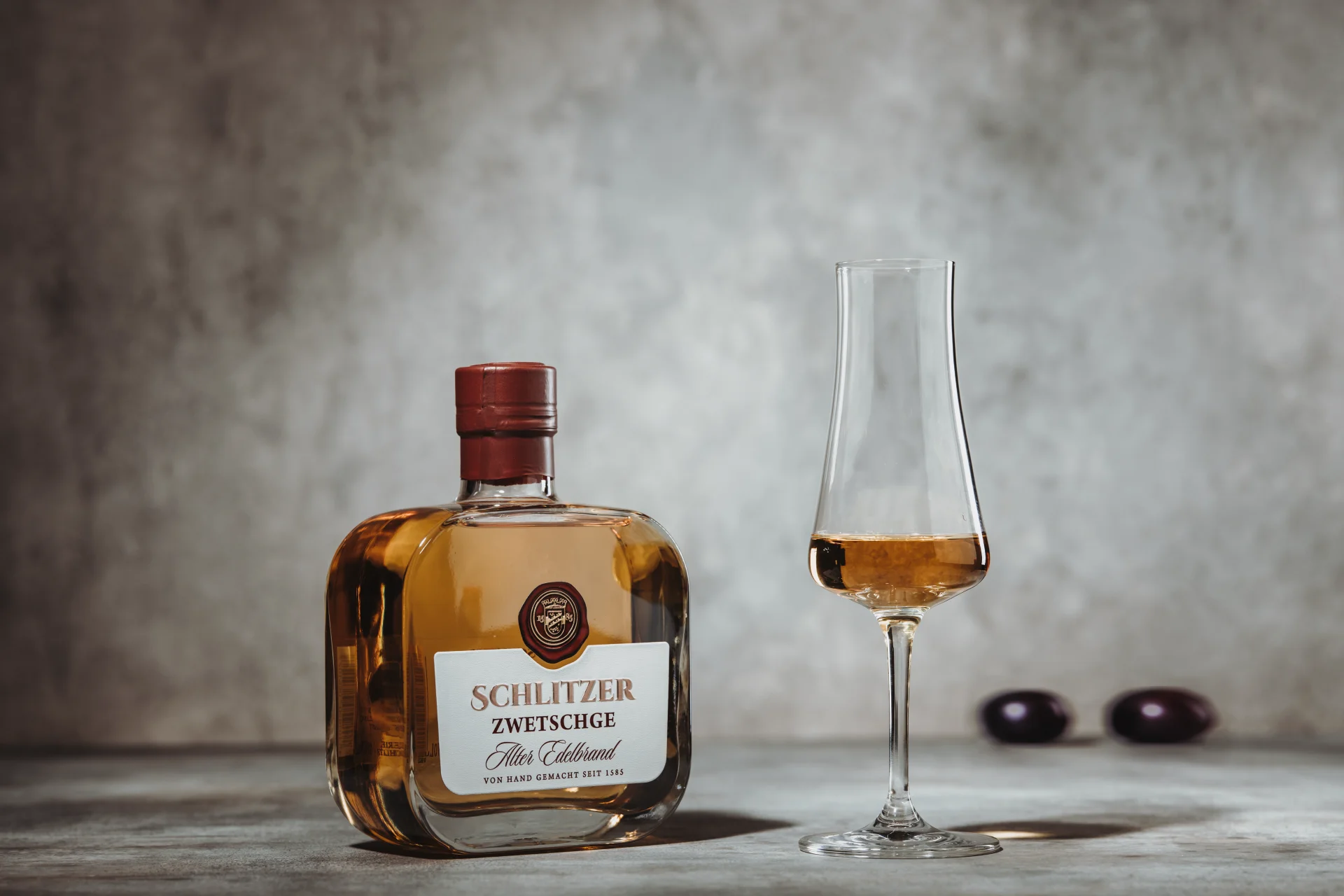 Edelbrand Zwetschge – Hochwertiger Zwetschgenschnaps aus traditioneller Destillation Flasche Edelbrand Zwetschge der Schlitzer Destillerie mit weißem Etikett und goldfarbenem Verschluss, stehend vor weißem Hintergrund.