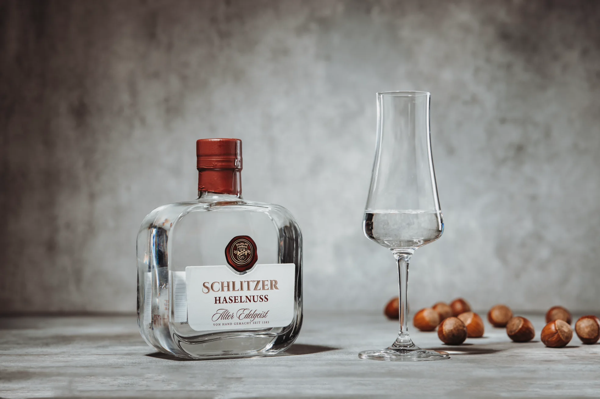 Haselnuss Geist – Edler Nussbrand aus der Schlitzer Destillerie Flasche Schlitzer Haselnuss Geist mit goldener Kapsel vor weißem Hintergrund – edle Spirituose mit intensivem Haselnussaroma aus der Schlitzer Destillerie.