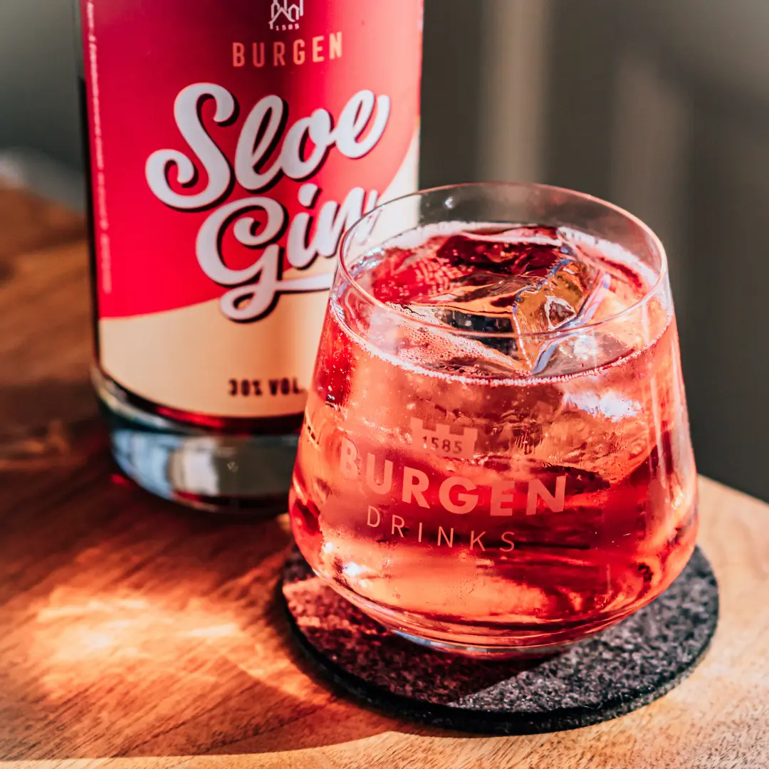 Burgen Sloe Gin – Fruchtiger Schlehengin in edler Flasche Flasche Burgen Sloe Gin auf weißem Hintergrund, rustikales Design mit dunkelrotem Etikett, gefüllt mit leuchtend rotem Schlehengin, Produkt der Schlitzer Destillerie.