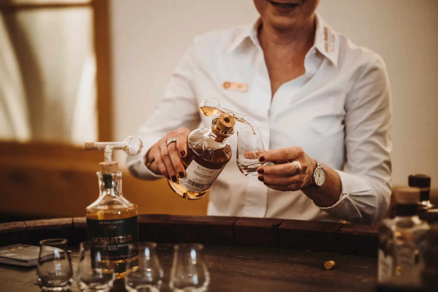 Whisky Tasting in der Schlitzer Destillerie mit edlen Spirituosen und stilvollem Ambiente Zwei Männer bei einer Whisky-Verkostung in der Schlitzer Destillerie, umgeben von Holzfässern in stimmungsvoll beleuchtetem Lagerraum.