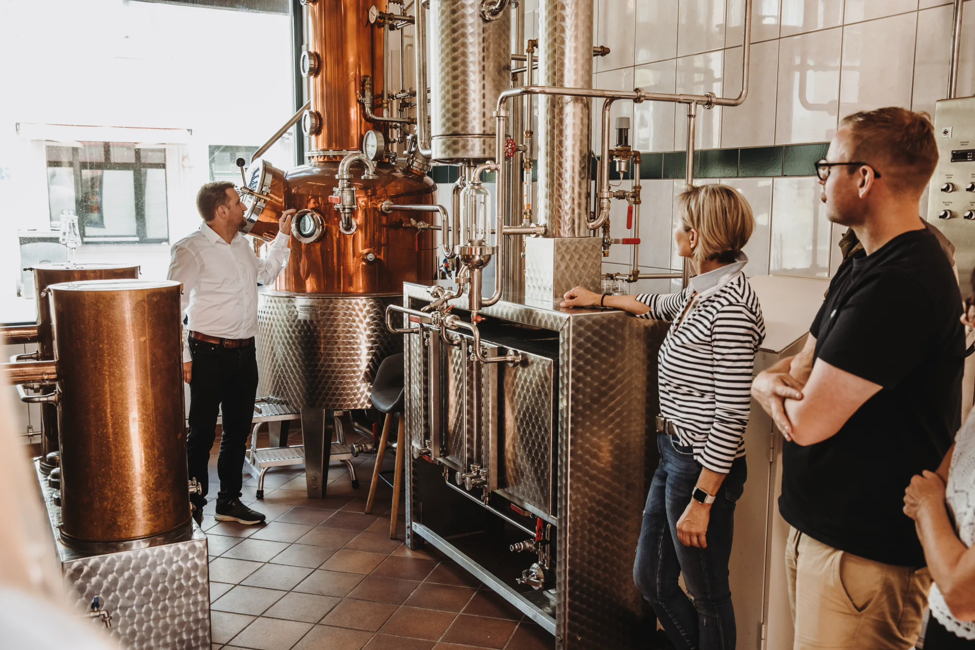 Besichtigung der Schlitzer Destillerie – Traditionelle Spirituosenherstellung erleben Mehrere Personen stehen in einer historischen Brennerei der Schlitzer Destillerie und lauschen bei einer Führung dem Guide vor einer Kupferbrennblase – Erlebnisführung im traditionsreichen Brennereibetrieb Hessens.