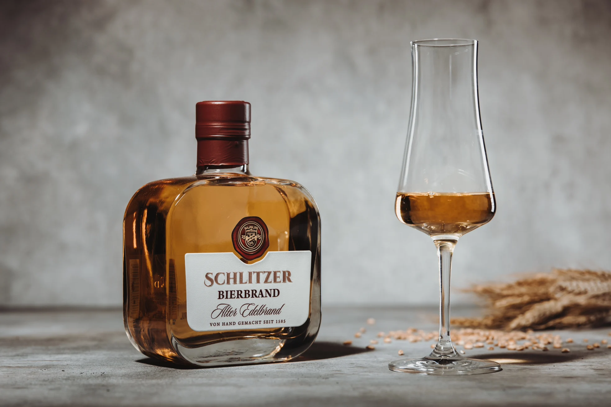 Gelagerter Bierbrand in eleganter Flasche auf Holzuntergrund Flasche Schlitzer Bierbrand gelagert mit Holzfass-Optik-Etikett auf hellem Hintergrund – hochwertiger deutscher Bierbrand in edler Verpackung.