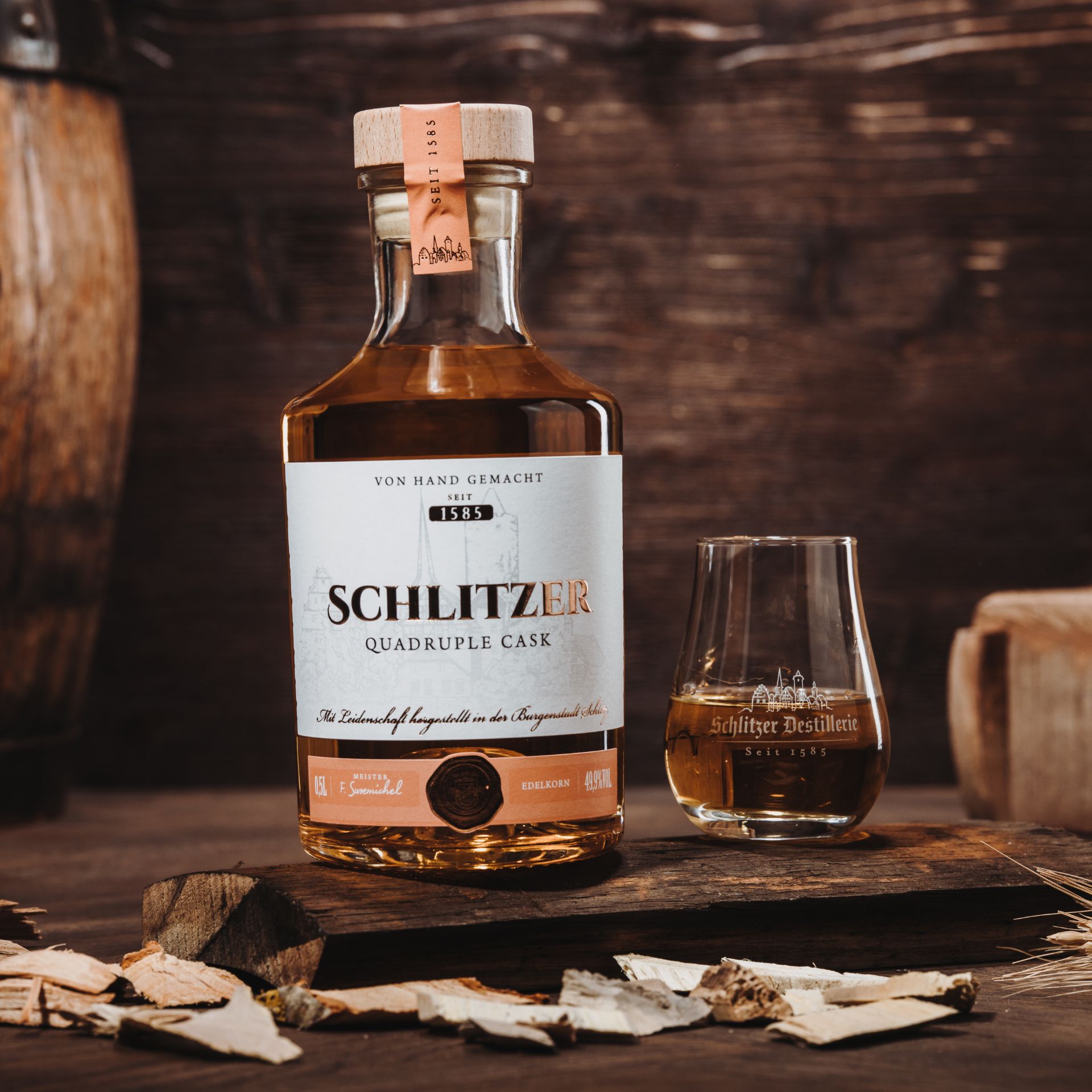 Flasche Schlitzer Quadruple Cask Whisky vor hellem Hintergrund – edles Design mit dunklem Etikett, goldener Schrift und Holzverpackung, Premium-Spirituose aus der Schlitzer Destillerie.