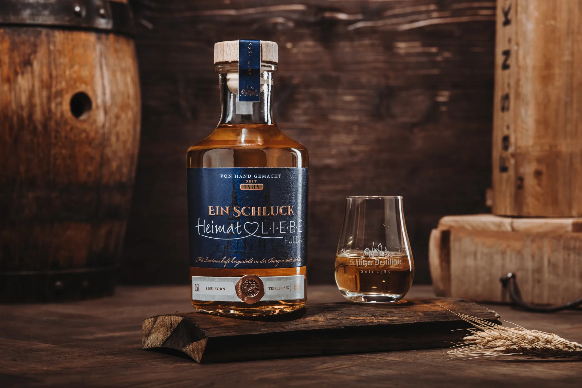 Flasche „Heimat Liebe Korn“ der Schlitzer Destillerie aus Hessen, stehend vor neutralem Hintergrund; transparentes Glas mit hellem Inhalt, Etikett in Rot und Weiß mit Schriftzug und Logo deutlich sichtbar.