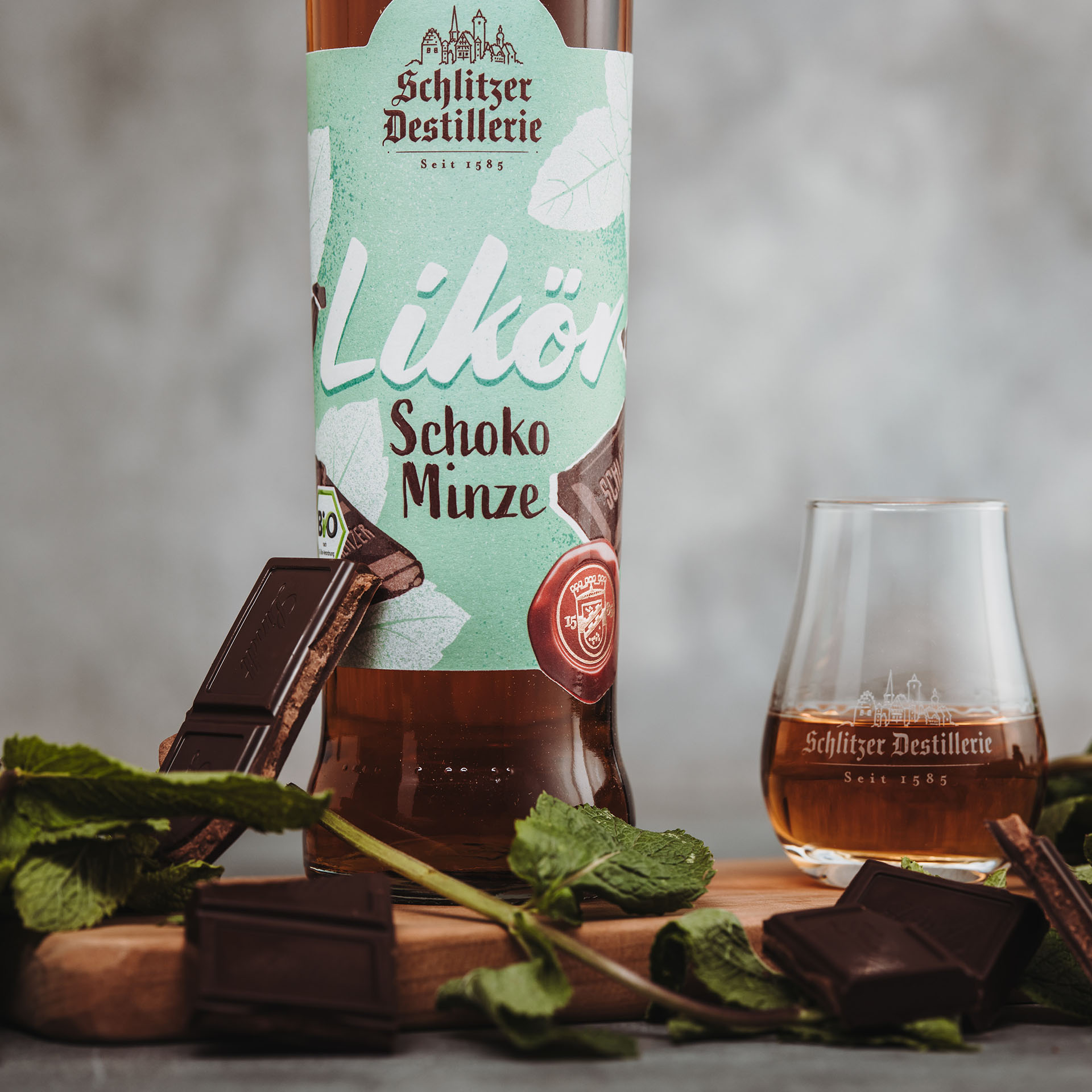 Schoko Minze Bio Likör - Hochwertiger Genuss aus der Schlitzer Destillerie Bio Schoko Minze Likör von Schlitzer Destillerie, abgebildet als Webshop Image mit Flasche eines Bio-Zertifizierten Likörs aus natürlichen Zutaten, verführerische Kombination aus Schokolade und Minze, Präsentation vor neutralem Hintergrund