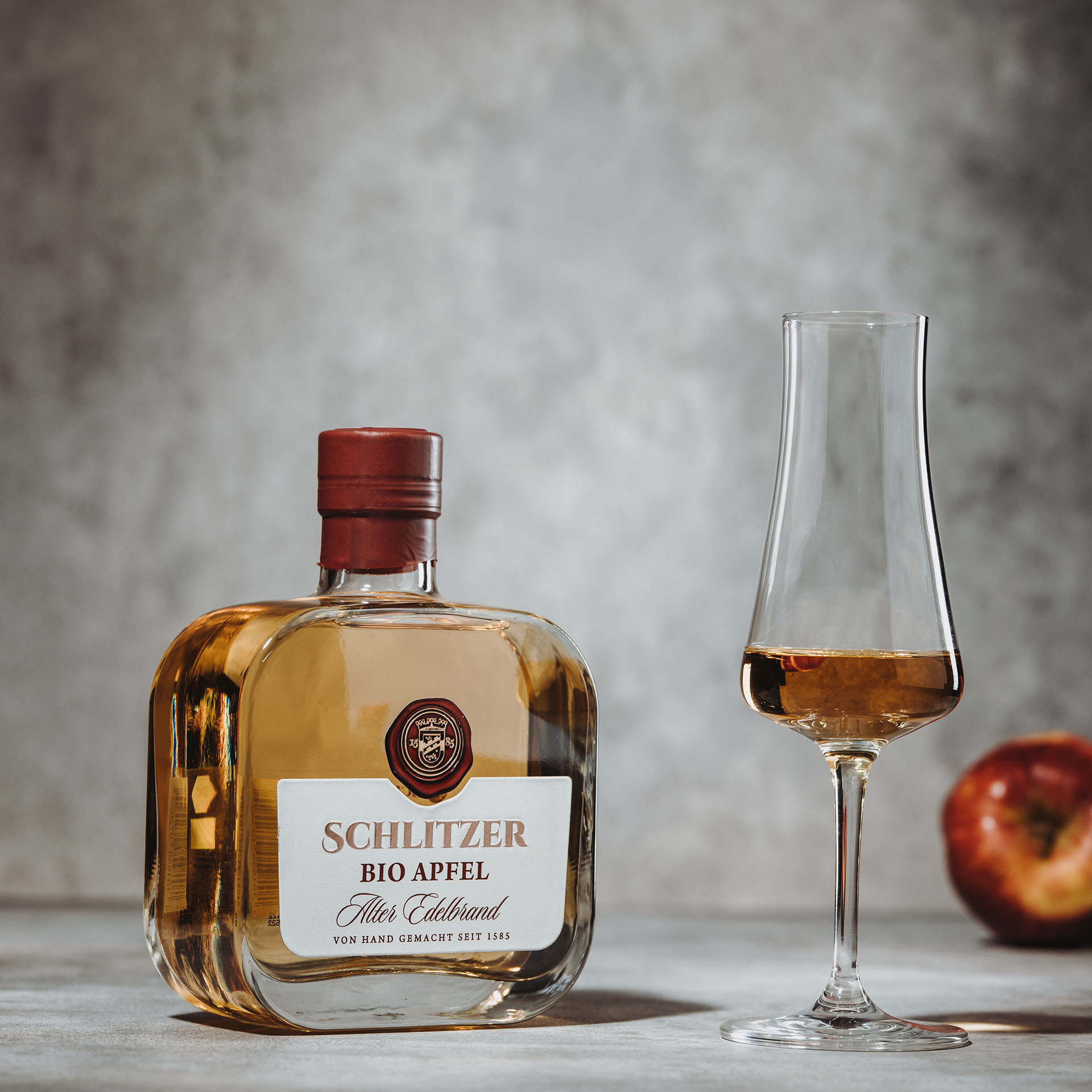 Schlitzer Alter Bio-Apfel-Brand - Hochwertiger Bio-Obstbrand aus der Schlitzer Destillerie Schlitzer Alter Bio-Apfel-Brand in eleganter Glasflasche mit Etikett, 700ml, vor weißem Hintergrund. Hochwertiger, biologischer Apfelbranntwein aus der Schlitzer Destillerie, geeignet für Genießer edler Spirituosen.