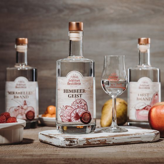 Traditionelle Obstbrände aus regionalem Anbau – Schlitzer Destillerie Verschiedene Obstbrände in eleganten Glasflaschen mit Etiketten der Schlitzer Destillerie, stilvoll arrangiert auf einem Holztisch vor dunklem Hintergrund, symbolisieren hochwertige, handwerklich hergestellte Spirituosen.