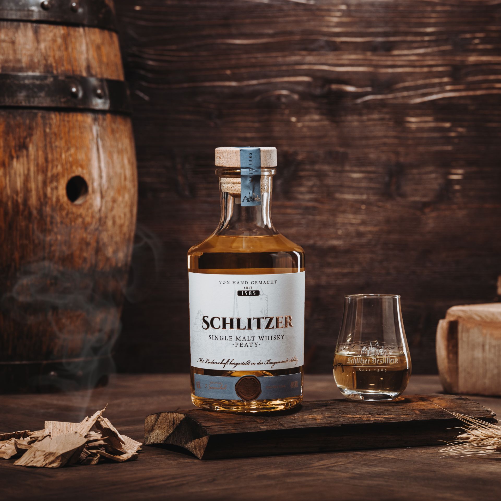 Flasche Schlitzer Single Malt Peaty Whisky vor weißem Hintergrund, mit elegantem, dunklem Etikett und naturbelassenem Korkverschluss – rauchiger deutscher Whisky der Schlitzer Destillerie.