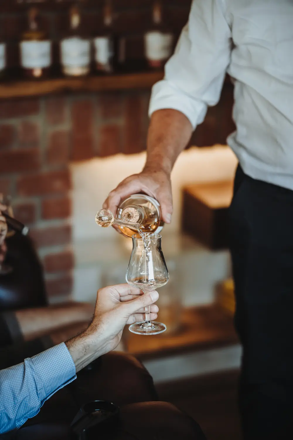 Schlitzer Whisky Tasting – Exklusive Spirituosenverkostung in stilvollem Ambiente Mehrere Flaschen Schlitzer Whisky mit unterschiedlichen Etiketten stehen auf einer Holzoberfläche; im Hintergrund ein stilvoll gedeckter Tisch mit Whiskygläsern – ideal für ein professionelles Whisky-Tasting.