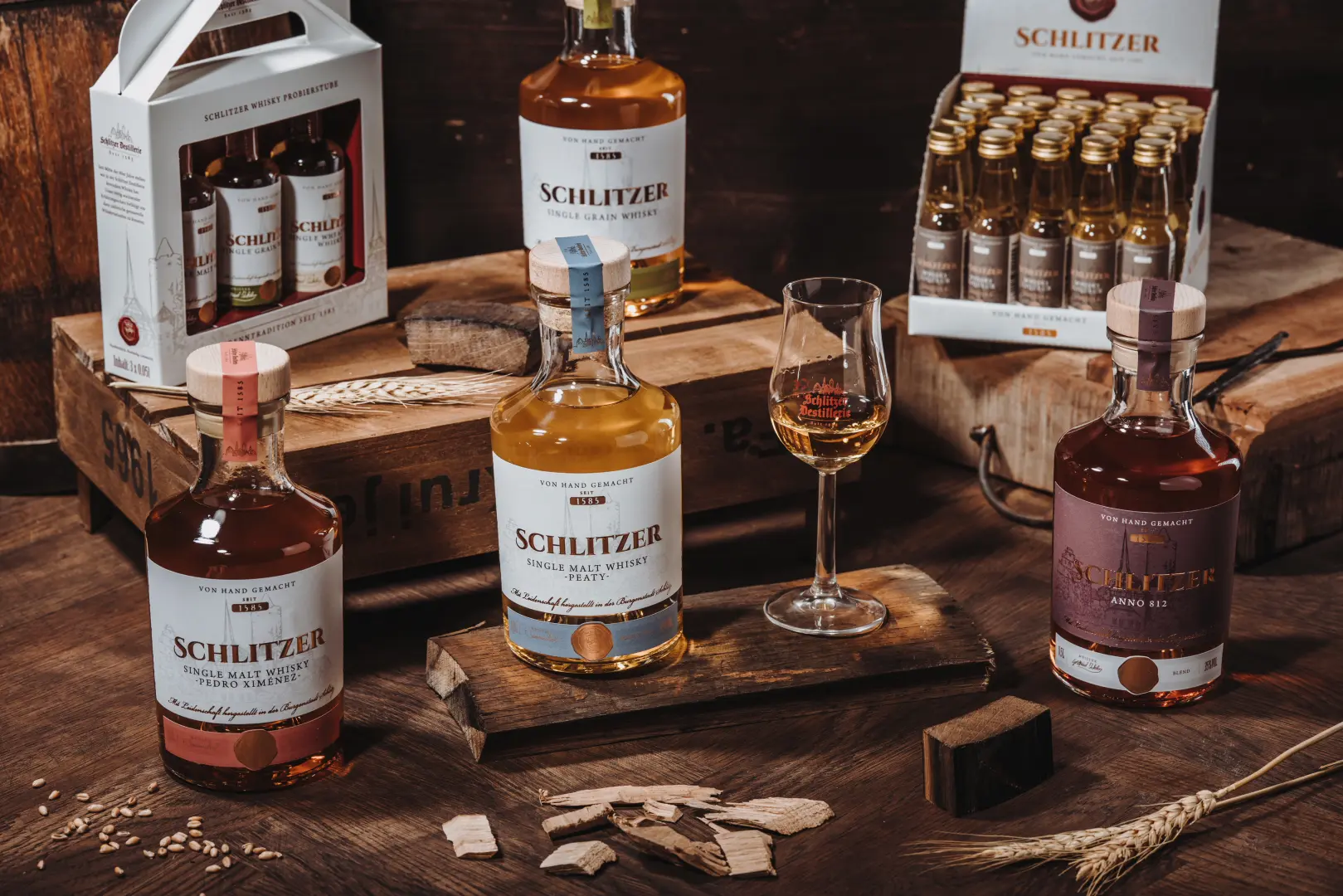 Verschiedene Whiskyflaschen der Schlitzer Destillerie stilvoll arrangiert auf Holzuntergrund Verschiedene Whiskyflaschen der Schlitzer Destillerie in edler Holzverpackung stilvoll arrangiert auf dunklem Hintergrund – hochwertige deutsche Whiskysorten in stimmungsvoller Präsentation.