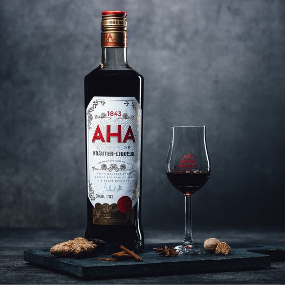 Aha Kräuterlikör – Traditioneller Kräuterlikör aus der Schlitzer Destillerie in Deutschland Flasche AHA-Kräuterlikör der Schlitzer Destillerie mit grünem Etikett, goldener Schrift und Schraubverschluss, stehend vor weißem Hintergrund.