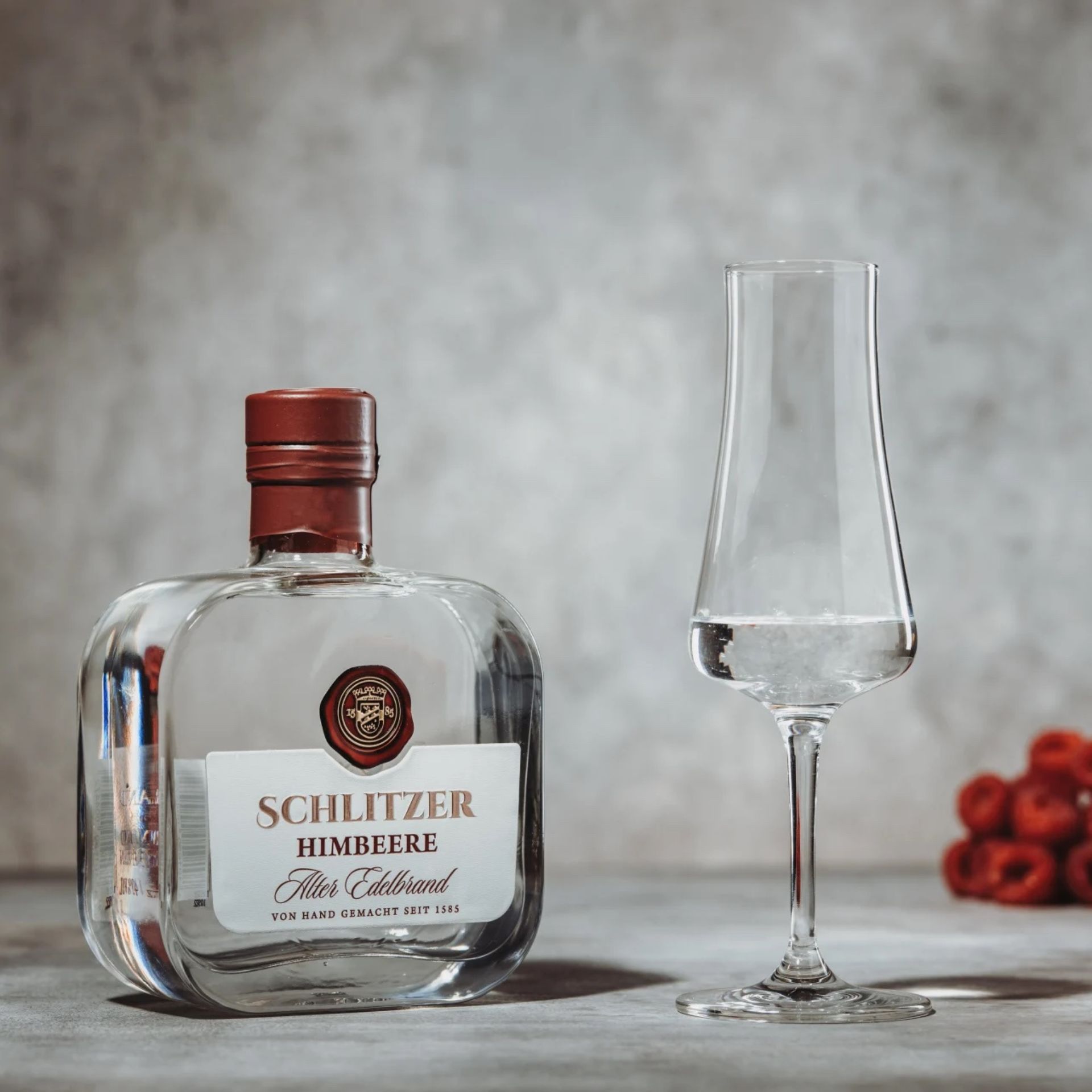Alter Himbeerbrand in edler Flasche – Schlitzer Destillerie Spezialität Flasche Alter Himbeer Brand der Schlitzer Destillerie auf hellem Hintergrund, edles Design mit goldener Schrift und roter Kapsel, hochwertiger Obstbrand aus reifen Himbeeren.