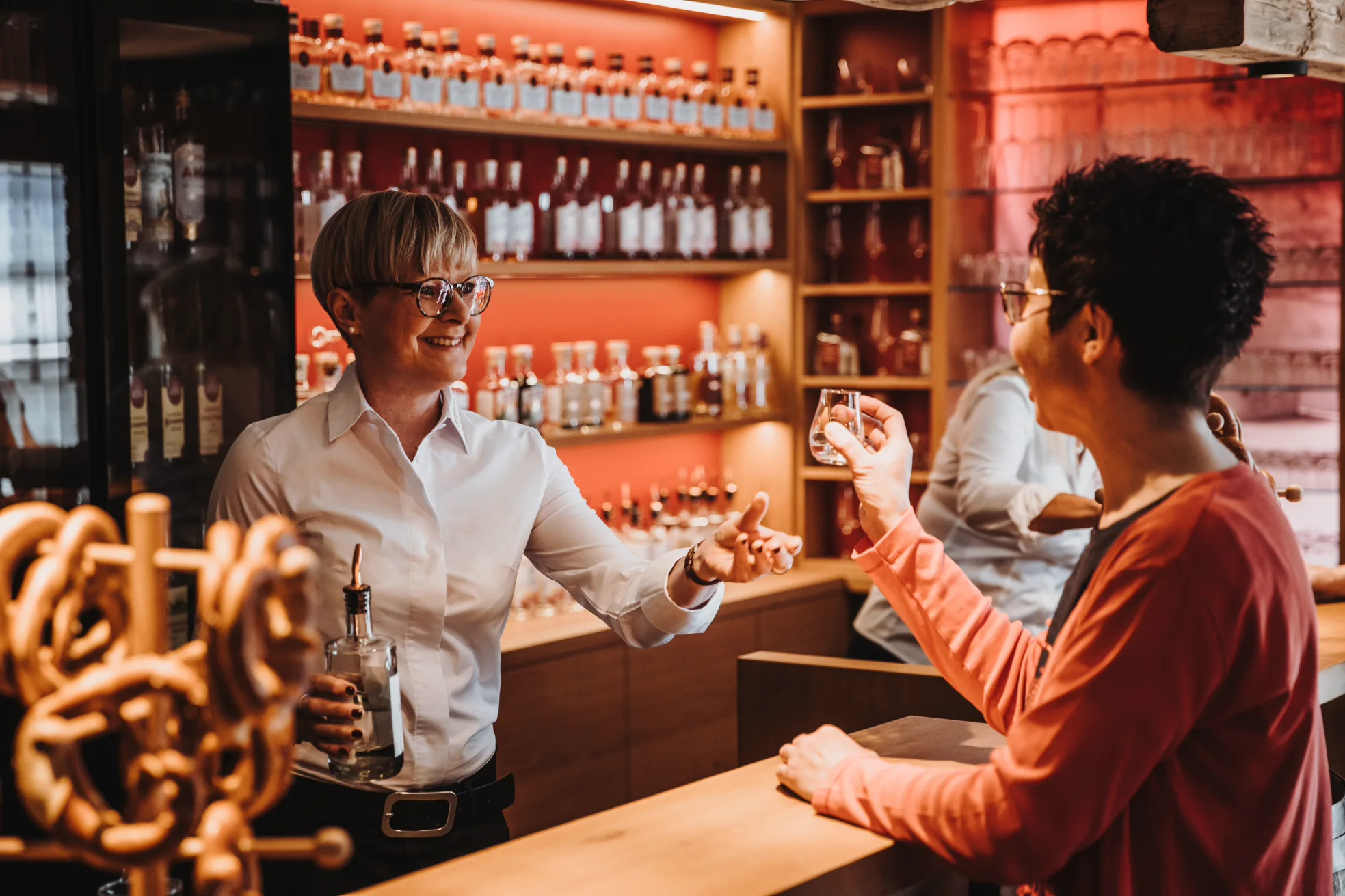 Whisky-Tasting in der Schlitzer Destillerie – Genusserlebnis in historischem Ambiente Drei Personen bei einem Tasting in der Schlitzer Destillerie, probieren verschiedene Spirituosen an einem rustikalen Holztresen in stimmungsvoller Atmosphäre.