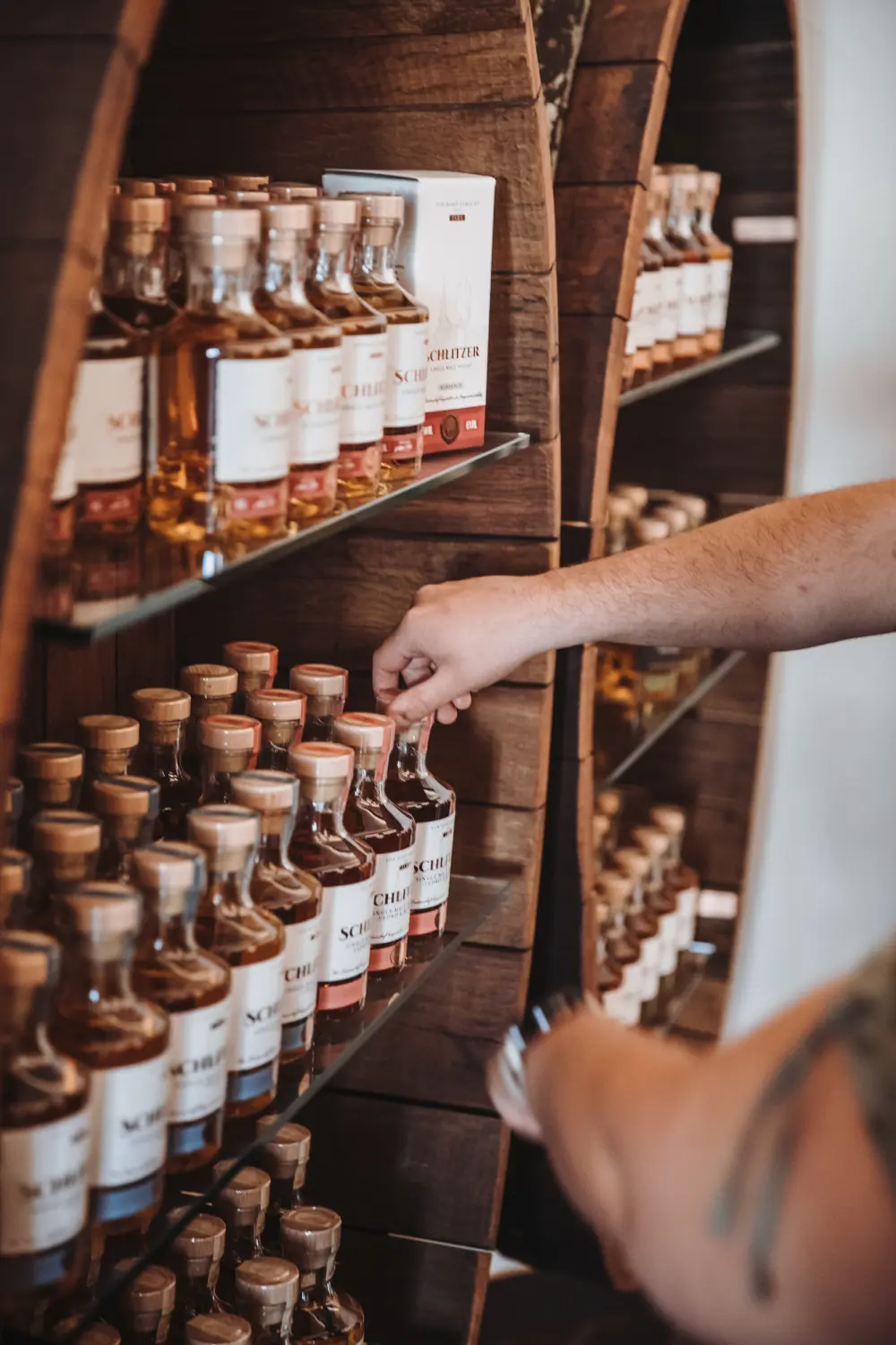 Whisky-Regal der Schlitzer Destillerie mit edlen Spirituosen-Flaschen Regal mit verschiedenen Whiskyflaschen der Schlitzer Destillerie, ordentlich nebeneinander aufgereiht, in einem hell beleuchteten Verkaufsraum aus Holz – Premium-Whisky aus Deutschland.